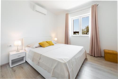 Un dormitorio blanco con una cama blanca y una ventana en Village apartments Mimi, en Pridvorje