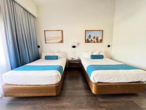 two beds in a hotel room with blue and white sheets at San Nicolas Hotel Casino in Ensenada