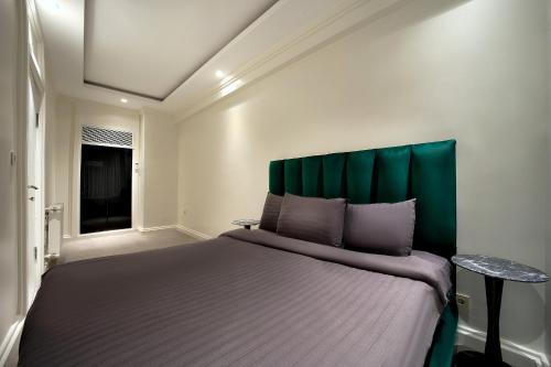 a bedroom with a large bed with a green headboard at Walton Gardens Pera in Istanbul