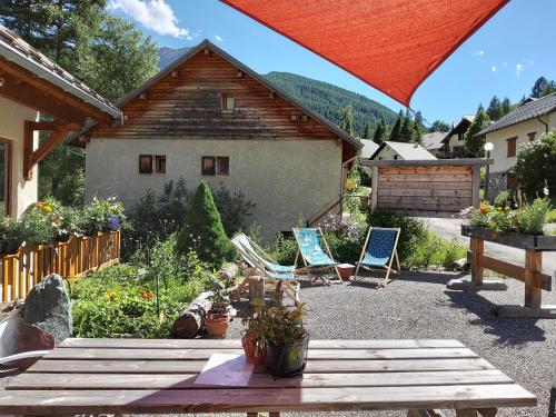 a backyard with two chairs and a table and a house at Gîte Ancolie Bleue in Abriès