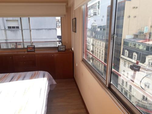 a bedroom with a large window with a view of a city at 4 Ventanales sobre la Avenida Corrientes in Buenos Aires