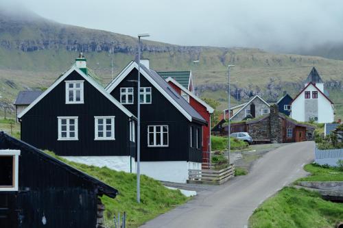 eine Gruppe von Häusern auf einem Hügel mit einer Straße in der Unterkunft Authentic Faroese House / Unique Location / Nature in Hellur
