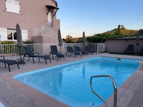 une petite piscine avec des chaises et un bâtiment dans l'établissement Oustaou di Ercole, à Bormes-les-Mimosas