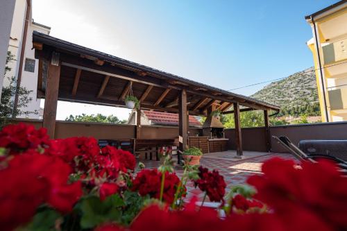 a patio with red flowers in front of a building at Lucija in Starigrad-Paklenica