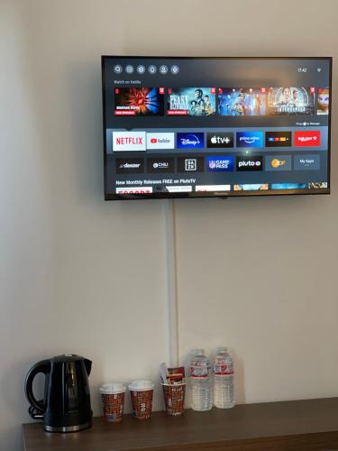 a television on a wall with cups of water at Hotel Casa Andalucia in Hallbergmoos