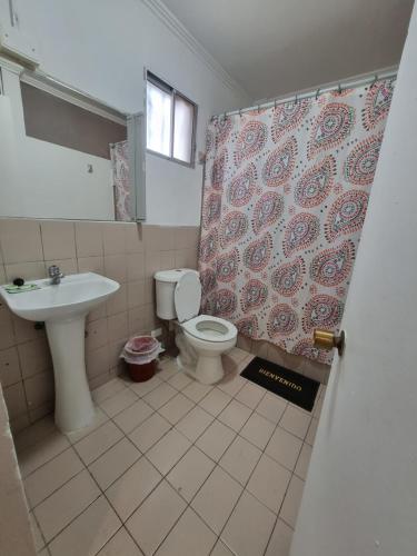 a bathroom with a toilet and a sink and a shower curtain at HOTEL ASTORE Matta 2537 in Antofagasta