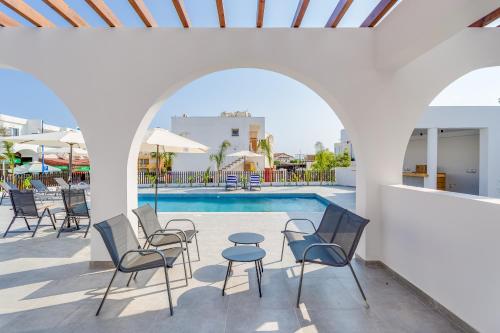 a pool with chairs and a table next to a pool at Zoi Ayia Napa in Ayia Napa