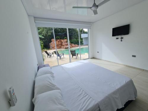 a white bedroom with a large bed and a large window at Quinta SHADDAI MELGAR in Melgar