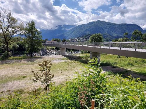 a bridge over a river with mountains in the background at Appartamento con giardino al Melograno in Locarno
