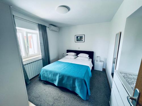 a bedroom with a bed with a blue blanket at Jakov Apartments in Orebić