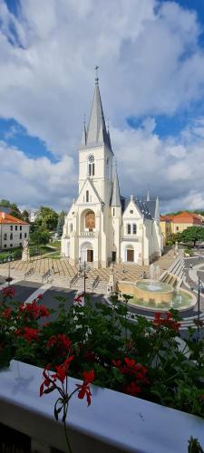 a large white church with a tower and a fountain at Hotel Kapos in Kaposvár