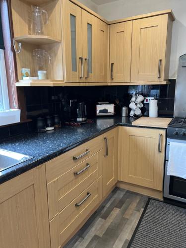 a kitchen with wooden cabinets and black counter tops at 4 bed bungalow near Airport in Edinburgh