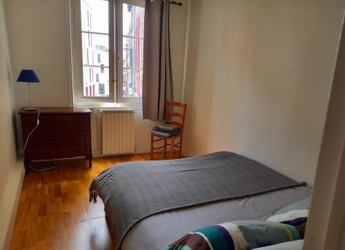 Schlafzimmer mit einem Bett, einem Schreibtisch und einem Fenster in der Unterkunft Appartement au coeur de Bayonne sur les remparts in Bayonne