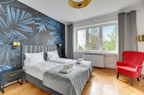 a bedroom with a bed and a red chair at Lion Apartments - Rio close to the beach and Monte Cassino in Sopot