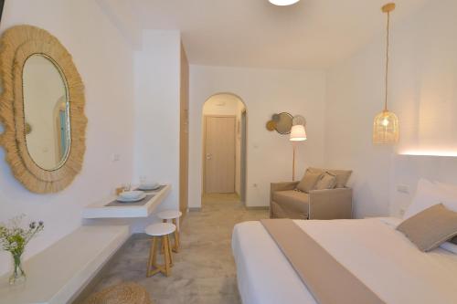 a bedroom with a bed and a mirror and a chair at Niriis Studios Aktaia & Glauke Batsi in Batsi