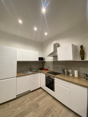 una cocina blanca con armarios blancos y fregadero en Appartement chic plage des Catalans en Marsella