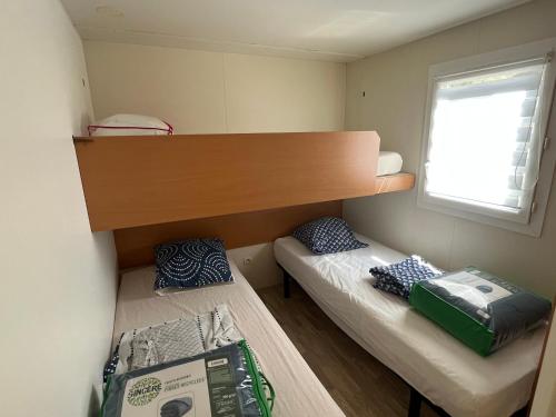 une petite chambre avec deux lits et une fenêtre dans l'établissement Mobil home bungalow 6 personnes villeneuve loubet plage marina baie des anges, à Villeneuve-Loubet