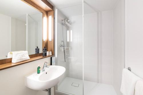 a white bathroom with a sink and a shower at greet hôtel Angoulême in Saint-Yrieix-sur-Charente