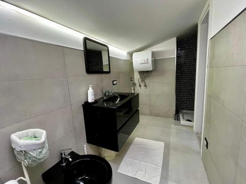 baño con lavabo negro y TV en la pared en Bilocale in pieno centro a Campobasso, en Campobasso