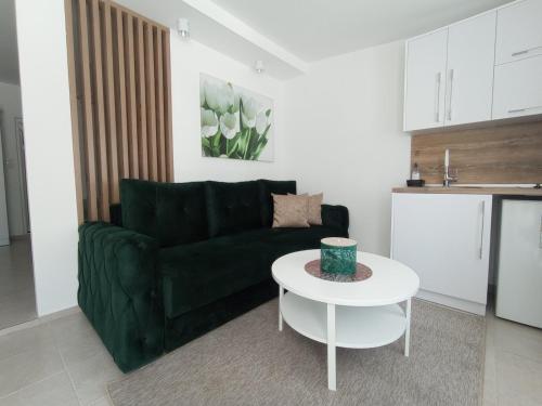 a living room with a green couch and a white table at Apartments Doha in Ulcinj