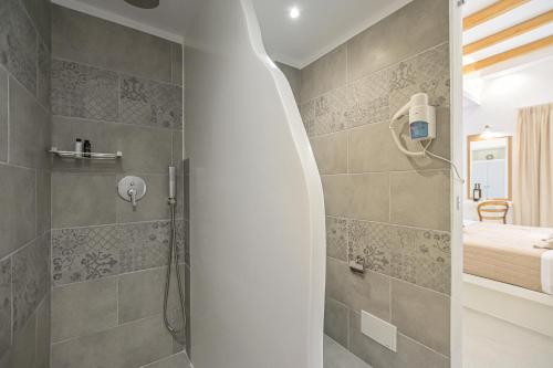a bathroom with a walk in shower next to a bed at Elite Suites Naxos in Naxos Chora