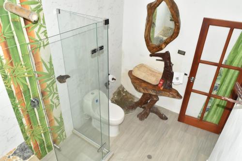 a bathroom with a toilet and a glass shower at Eco Hostal Kuima in El Zaino