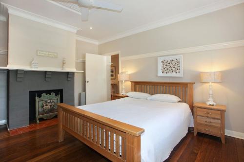 a bedroom with a white bed and a fireplace at Patch of Paradise Iluka in Tea Gardens