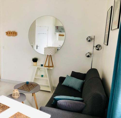 ein Wohnzimmer mit einem Sofa und einem Spiegel in der Unterkunft Studio lumineux Saint-Ideuc à 1km de la plage in Saint-Malo