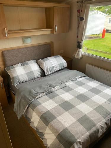 a bed in a small room with a window at Prestige Static Caravan on 5 Star Holiday Park in Cheswick