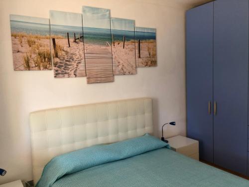 a bedroom with a bed with four paintings on the wall at Case dei limoni sul mare in Capoliveri