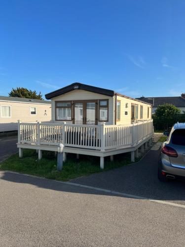 a house with a porch and a car parked in front of it at Seascape Camber Sands in Camber