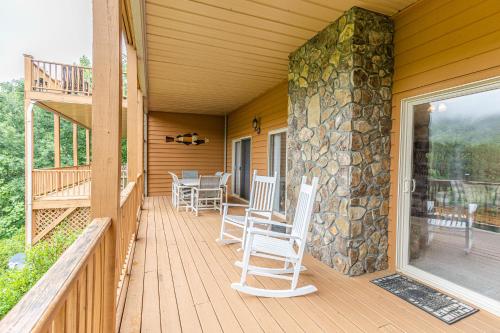 a porch with rocking chairs and a stone wall at Condo with Stunning Mountain and 6th Green views near Harrahs Cherokee Bryson City in Whittier
