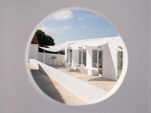 a view of a white house through a round window at CASASUPERTUBOS® Villa 9 & Apart 1-8 in Atouguia da Baleia