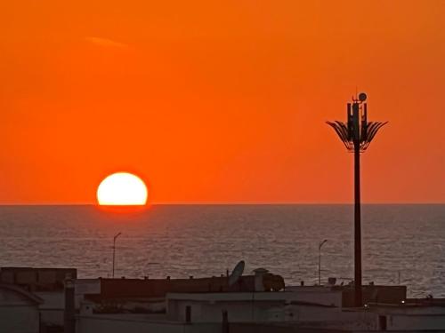 an orange sunset over the ocean with a street light at OceanParc - Vue sur Mer et Parc 24H Sécurité in Mohammedia