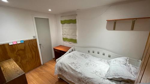 a bedroom with a white bed and a wooden floor at Calor De Hogar La Serena in La Serena