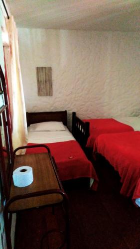 two beds in a room with red sheets and a table at Finca Campestre Rancho Alegre in Fusagasuga