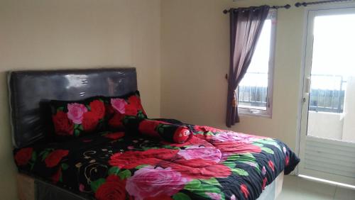 1 dormitorio con 1 cama con edredón de flores y ventana en wijayanti's villa en Probolinggo