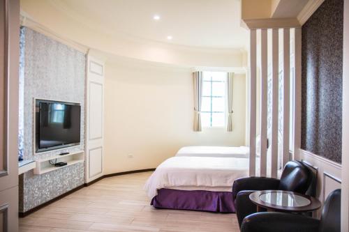 a hotel room with a bed and a tv and chairs at Chuan Cheng Castle in Magong