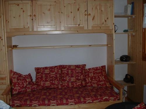 1 cama con edredón rojo y armarios de madera en Appartement Le Biot, 3 pièces, 6 personnes - FR-1-573-100 en Le Biot