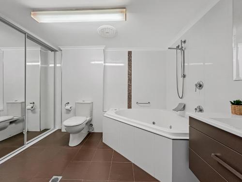 a bathroom with a tub and a toilet and a sink at Albacore Apartments in Merimbula