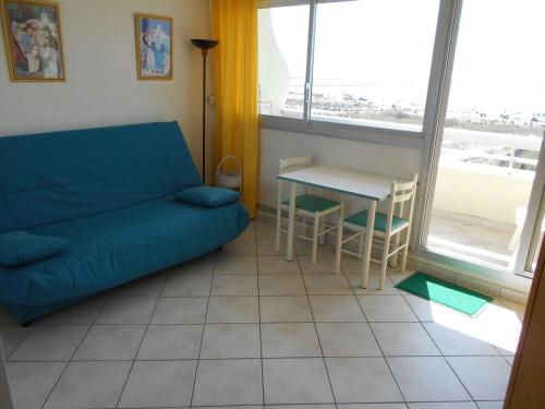 un salon avec un canapé bleu et une table dans l'établissement Studio climatisé avec piscine et parking - Port Camargue - FR-1-250-239, au Grau-du-Roi