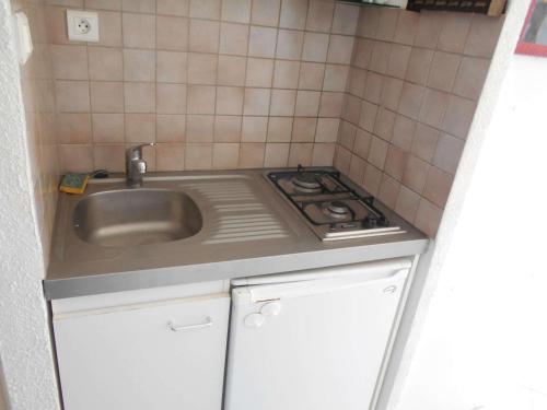 une petite cuisine avec un évier et une cuisinière dans l'établissement Studio climatisé avec piscine et parking - Port Camargue - FR-1-250-239, au Grau-du-Roi