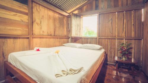 Un dormitorio con una cama con paredes de madera y una ventana en Posada Nativa Brisa y Mar, en Nuquí
