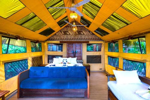 a bedroom with a blue couch in a room with windows at Barefoot Manta Island Resort in Drawaqa Island