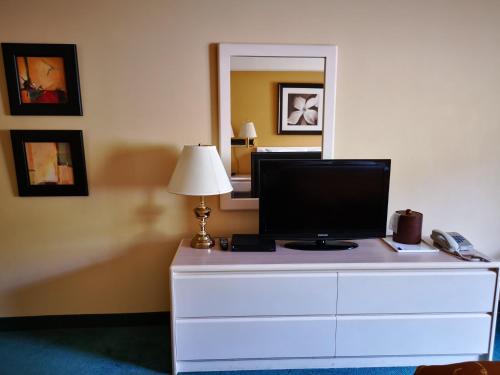 a television on a dresser with a lamp and a mirror at MountainView Hotel Merritt in Merritt