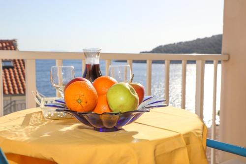 uma taça de fruta numa mesa com uma garrafa de vinho em Apt and rooms Marlene - 50 m from sea em Milna