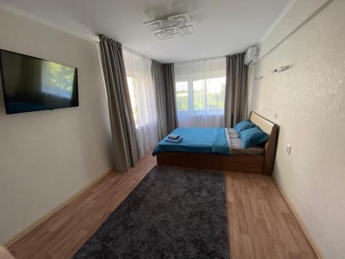 a bedroom with a bed and a flat screen tv at Апартаменты Балхаш in Balqash