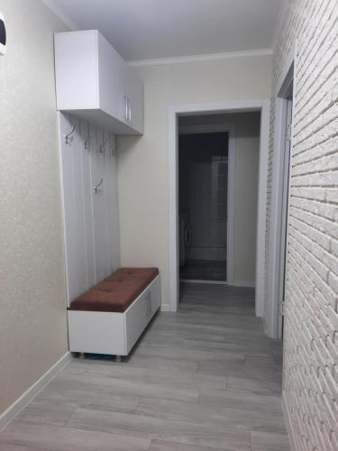 un pasillo con un banco en una habitación blanca en 2-х комнатная Квартира, en Uralsk