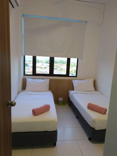 two beds in a room with a window at Daddy's GuestHouse IMPERIO ALOR SETAR in Alor Setar