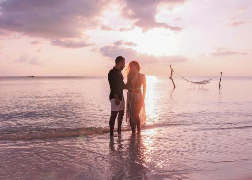 a couple standing on the beach at sunset at Furaveri Maldives in Raa Atoll